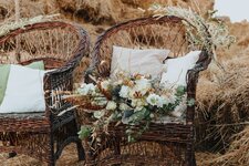 two-wicker-chairs-with-white-cushions-and-a-bouquet-of-flowers-on-it-rattan-chairs-with-straw-...jpg