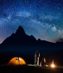 romantic-pair-tourists-in-his-camp-at-night-near-campfire-and-tent-against-high-mountains-back...jpg