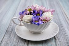 side-view-of-flowers-in-cup-on-saucer-on-wooden-background_141793-49505.jpg